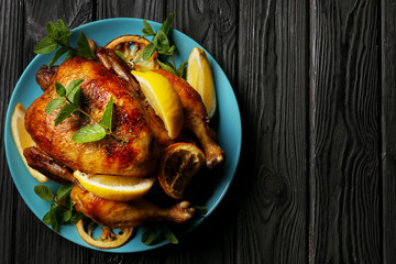Homemade baked chicken with lemon and mint on wooden background