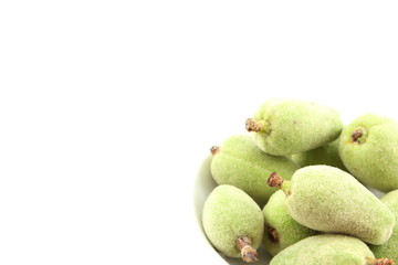 fresh green almond fruits in a small white bowl