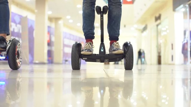Teenager on hyroscooter in a modern shopping center. Close up of man's legs on two wheels electric gyro scooter