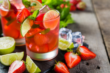 Strawberry mojito and ingredients on rustic background