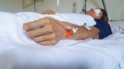 Surgical patient lying on a hospital bed with one eye blindfolded