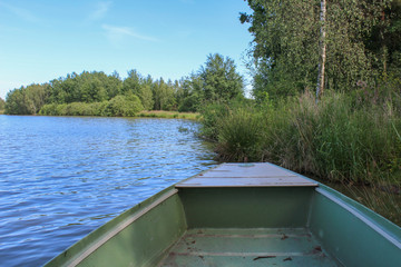 Boat on pond with trees and sky. Czech landscape