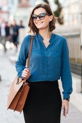 Smiling lovely woman in sunglasses on a street