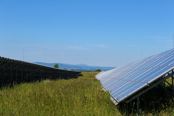 Photovoltaic solar panels with grass in czech landscape.