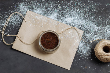 loose scrub in brown glass small jar Kraft on package jute thread of brilliant white snow on dark gray black background close-up
