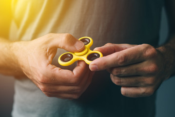 Yellow fidget spinner in male hand - Powered by Adobe