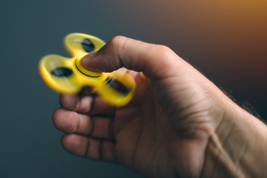 Yellow fidget spinner in male hand
