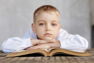 Weary young boy bored with reading