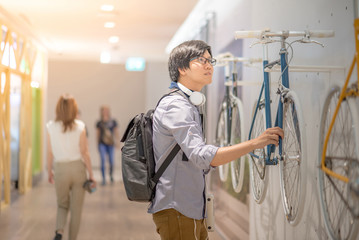Naklejka premium Young Asian man looking vintage bicycle at bike shop in department store, urban lifestyle concept