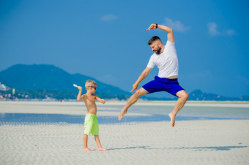 Father and son having fun on the desert sunny beach