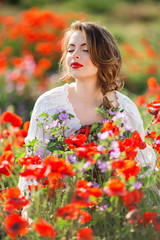 Pretty woman in field of red poppy flowers, spring time