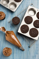 Decorating Chocolate Cupcakes with Frosting in Pastry Bag
