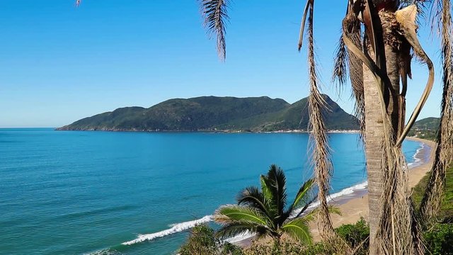 Praia, colina e c&eacute;u azul.