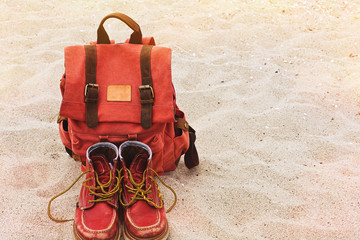 Vintage backpack and worn boots on the sand beach
