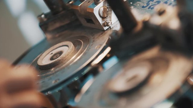 Male hands assembles precise metal machine with circular markings, putting rins inside holes, close up