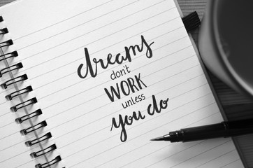 DREAMS DON’T WORK UNLESS YOU DO motivational quote written in notebook