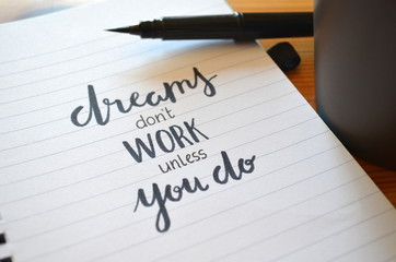 DREAMS DON’T WORK UNLESS YOU DO motivational quote written in notebook