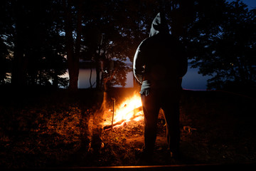 ghost standing near man, while he standing near campfire in night