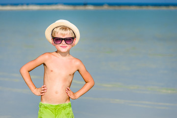 Portrait of a handsome seven years old boy on the desert sunny beach