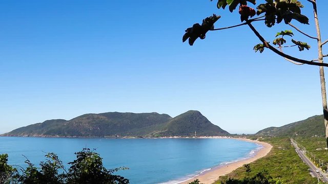 Praia, colina e c&eacute;u azul.