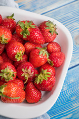 Ripe red strawberries in white bowl.