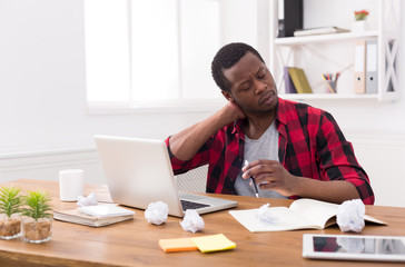 Obraz na płótnie Canvas Overworked black businessman in casual office, work with laptop