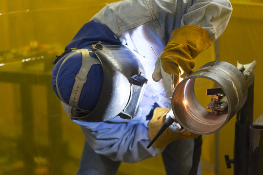 The welding craftsman welding the steel tube and ware the safety mask.Heavy  industrial concept