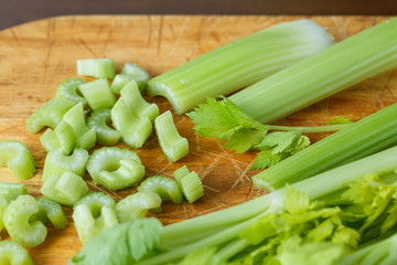 Fresh celery cut into small pieces on wooden board