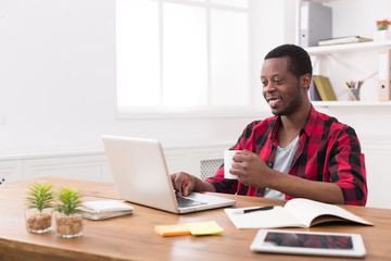 Happy black businessman in casual office, work with laptop