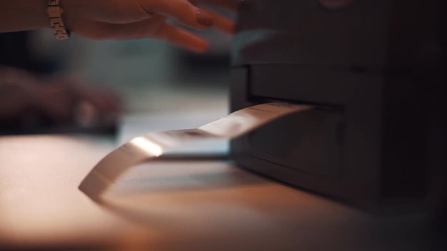 Woman hand with golden wrist watch printing out sticker patch with product information in office