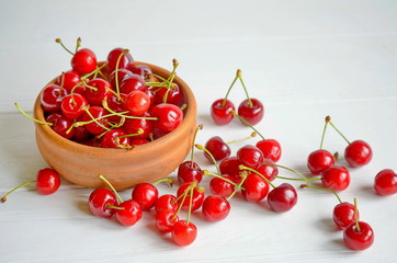 Obraz na płótnie Canvas Brown ceramic bowl of fresh and tasty cherries on wooden white background
