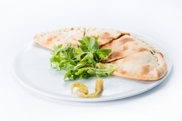 Sliced spicy closed pizza on a plate. Calzone