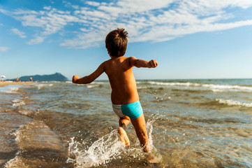 child running free into sea at the beach in summer day
