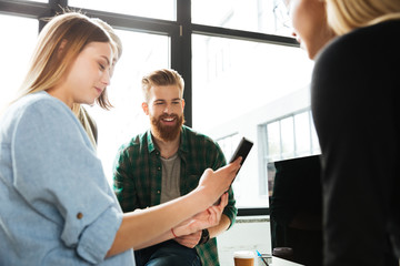 Young colleagues standing in office using tablet computer