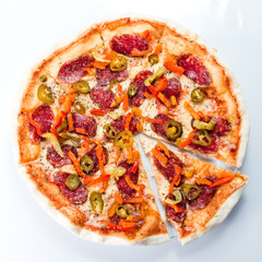 Sliced spicy Italian pizza with pepperoni and cheese on a light background