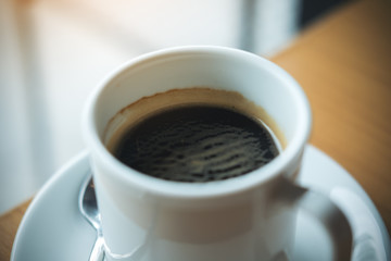 Closeup image of hot coffee cup on vintage wooden table in cafe