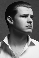 Male beauty, movie superstar concept. Portrait of young man from mafia clan with perfect haircut wearing white shirt. Old Hollywood classic style. Wet glossy hair. Close up. Monochrome studio shot