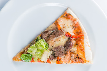 Slice of delicious pizza with beef and salad