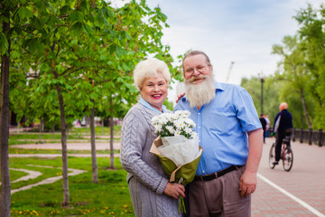 Attractive elderly couple walking around the city with a bouquet of flowers