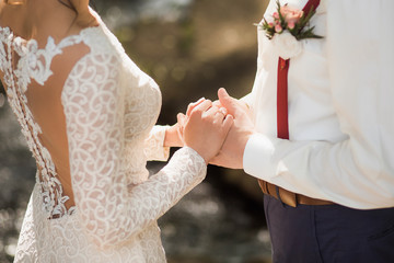 White bridal couple at wedding ceremony outdoors. Happy beautiful bride and handsome groom holding...