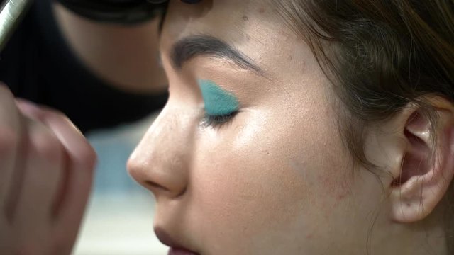 Man makeup artist making the face art with blue shadows
