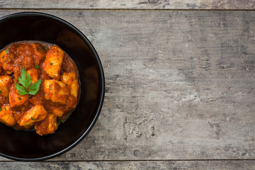 Chicken tikka masala in bowl on wooden table
