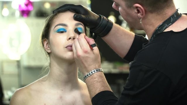 Man makeup artist making the face art for a woman