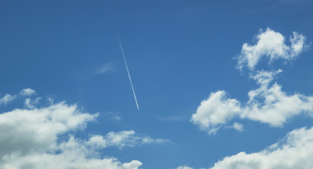 Blue sky with white clouds and flying plane