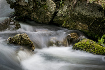 Mossy rock with the river . long exposure