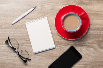 Blank white notebook open, eyeglass, pen and cup of coffee on the desk