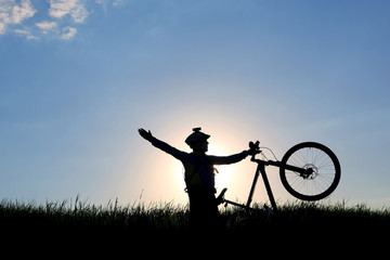 silhouette of a cyclist with a bike in the sun