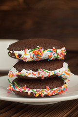 Chocolate cupcakes, Chocolate Whoopie pie with Confectioneryon the wooden table. vertical, selective focus