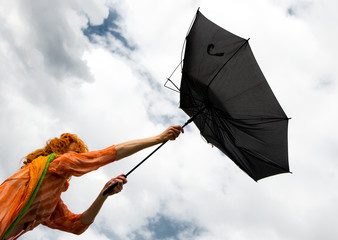 A woman tries to hold her umbrella in a strong wind
