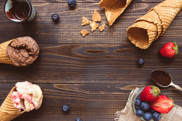 Ice-cream with fresh berries and chocolate sauce on the wooden background, top view. Copy space